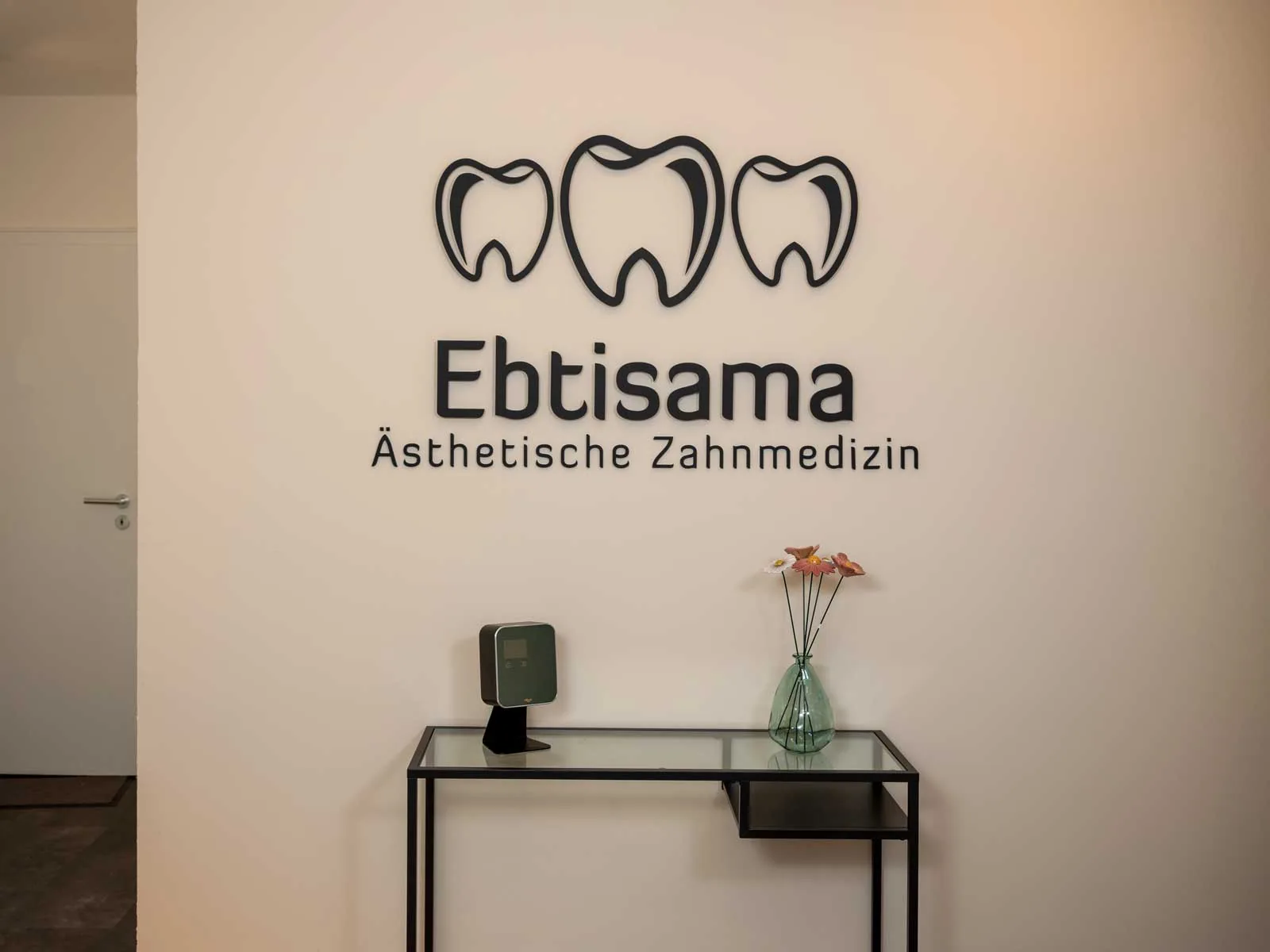 Empfang der Ebtisama Zahnarztpraxis in Köln-Holweide mit dem Praxislogo an der Wand